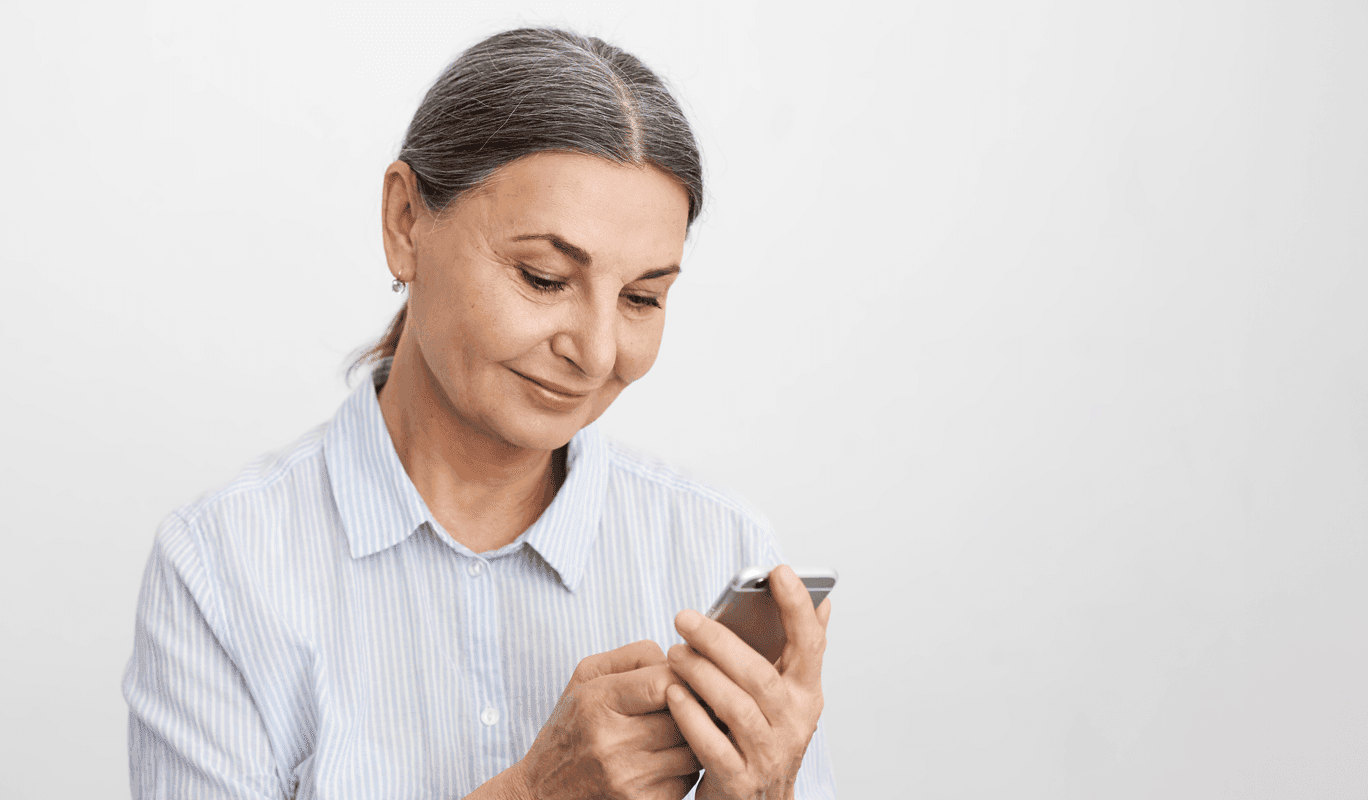 Mulher olhando para o celular e vendo o aplicativa da Clicare